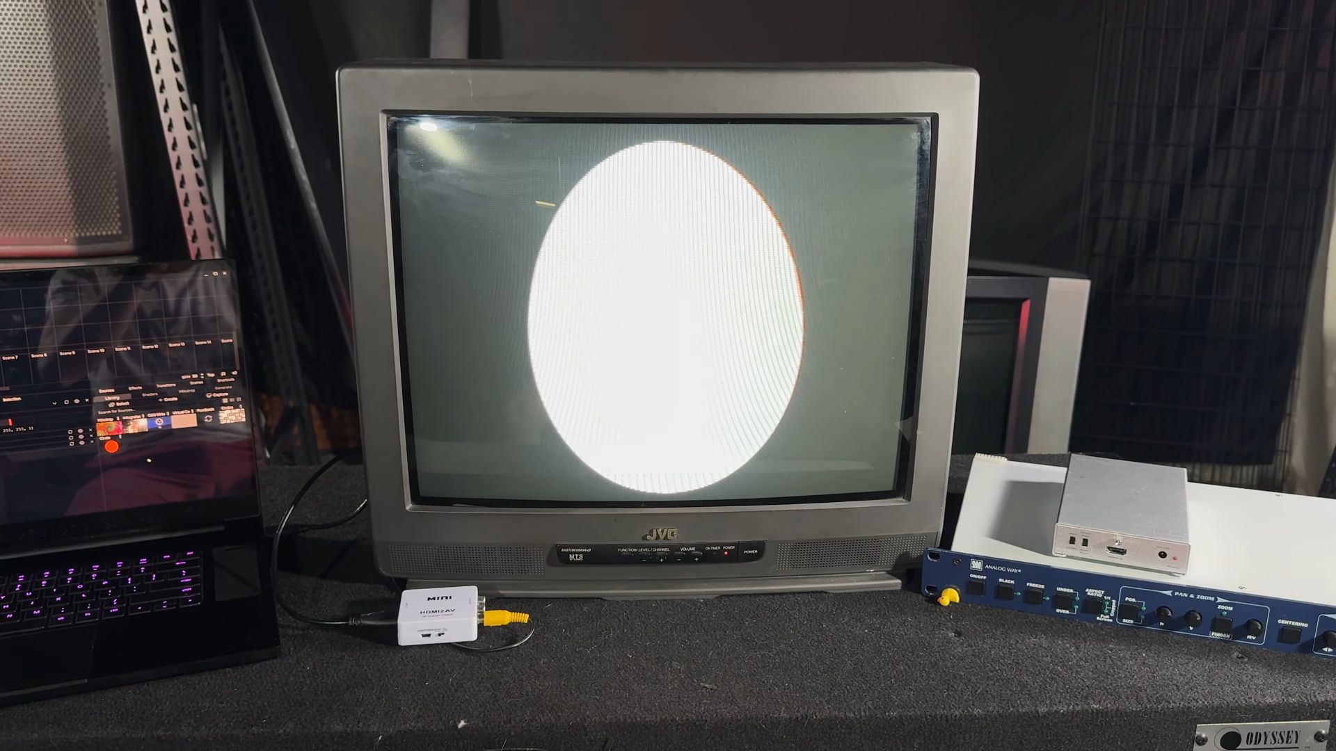 A vintage JVC CRT television displaying a squeezed, oval-shaped image instead of a circle due to an aspect ratio issue. Connected to a modern laptop via an HDMI to AV converter.