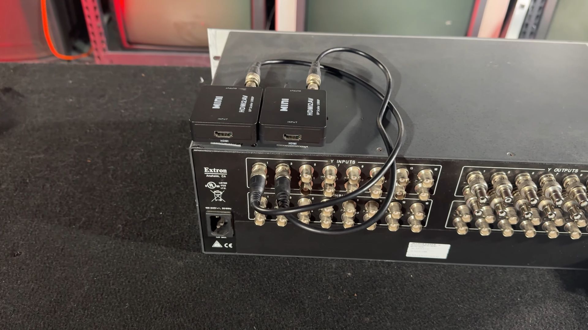 The back of an Extron matrix switcher, featuring BNC connectors for inputs and outputs, with two HDMI to AV converters attached for signal conversion.