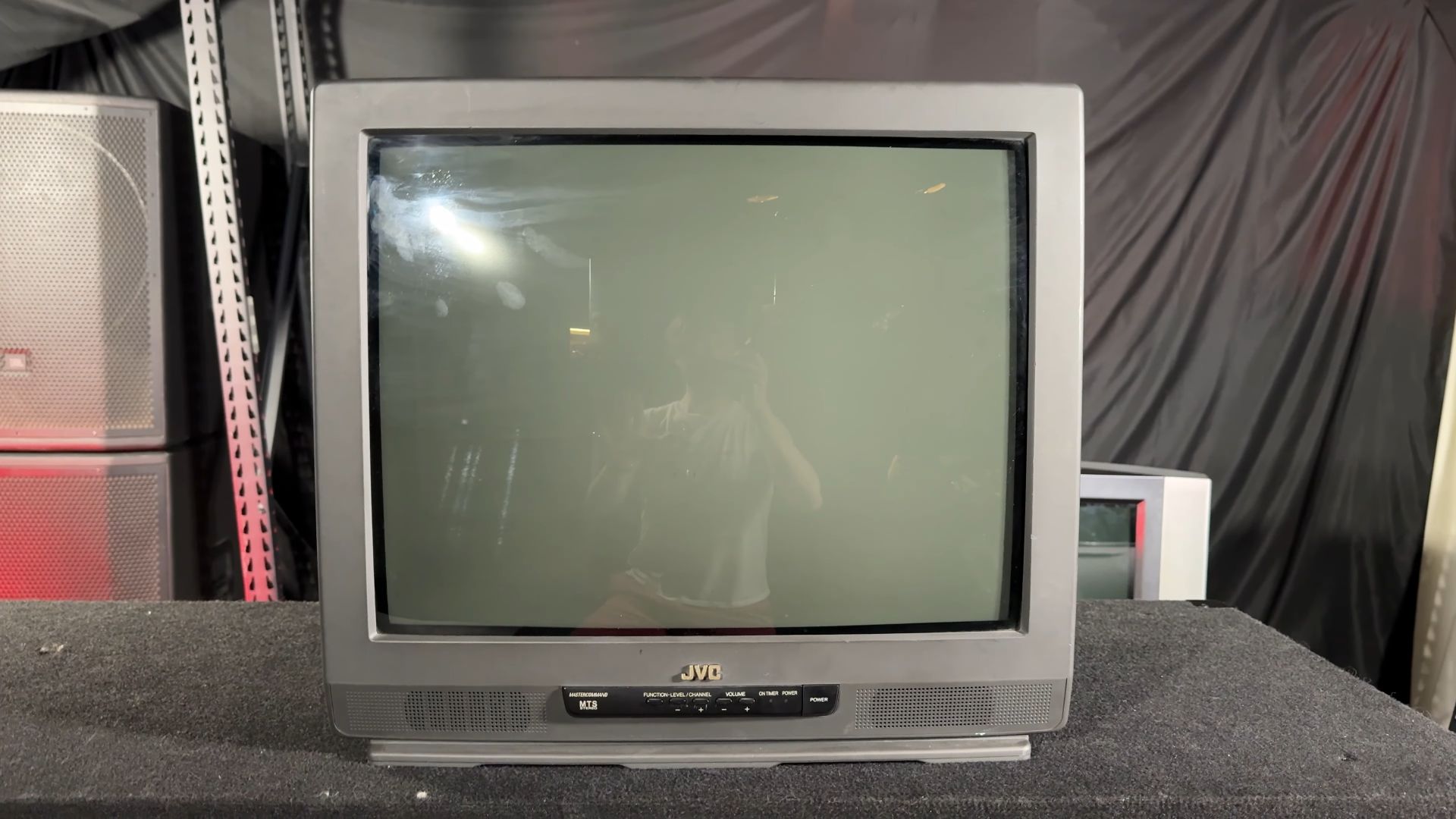 A vintage JVC CRT television on a table, featuring a square screen with minimal bezels, front control buttons, and built-in speakers at the bottom.