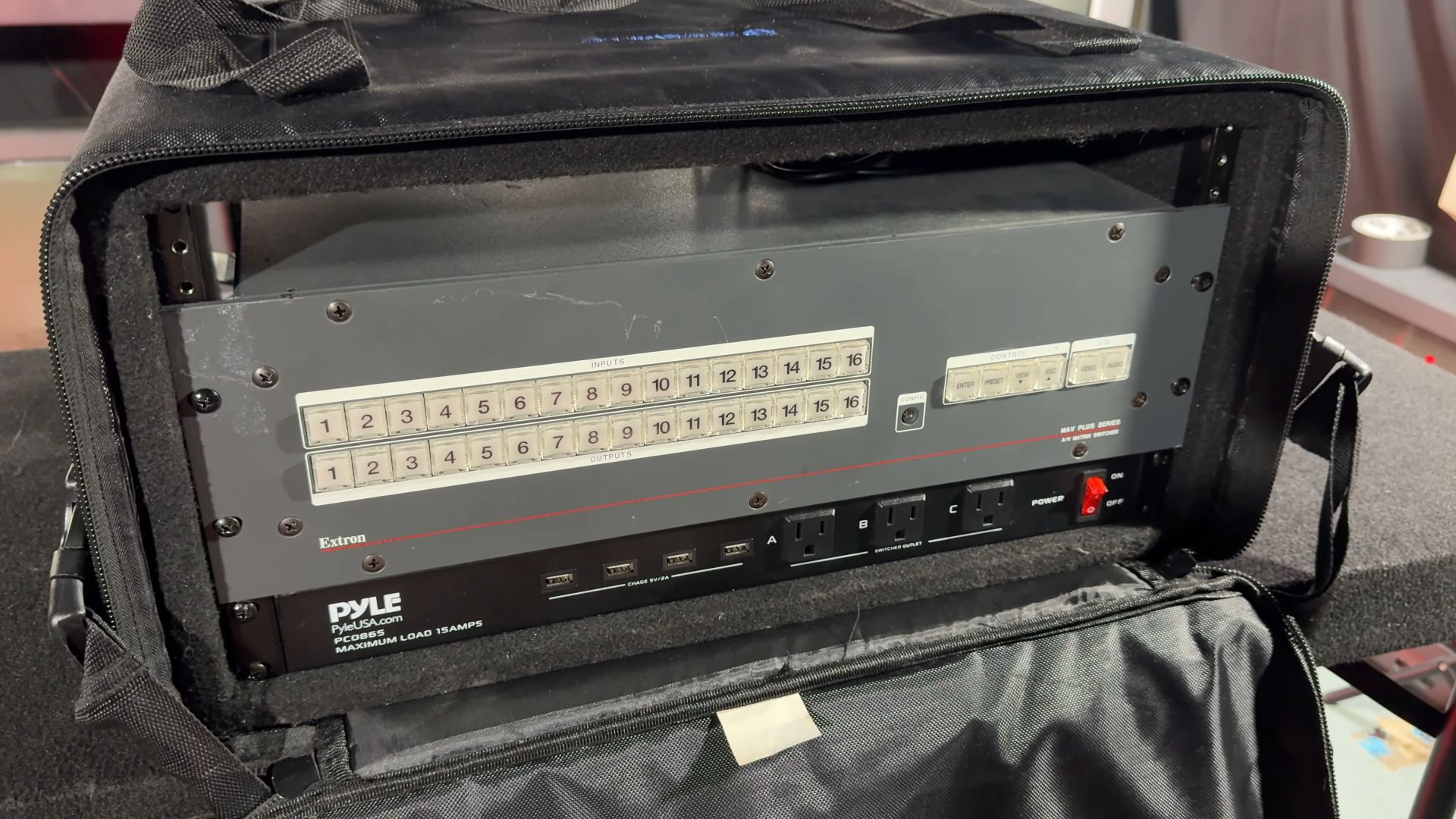 An Extron matrix switcher mounted in a portable rack case with a Pyle power distribution unit below it.