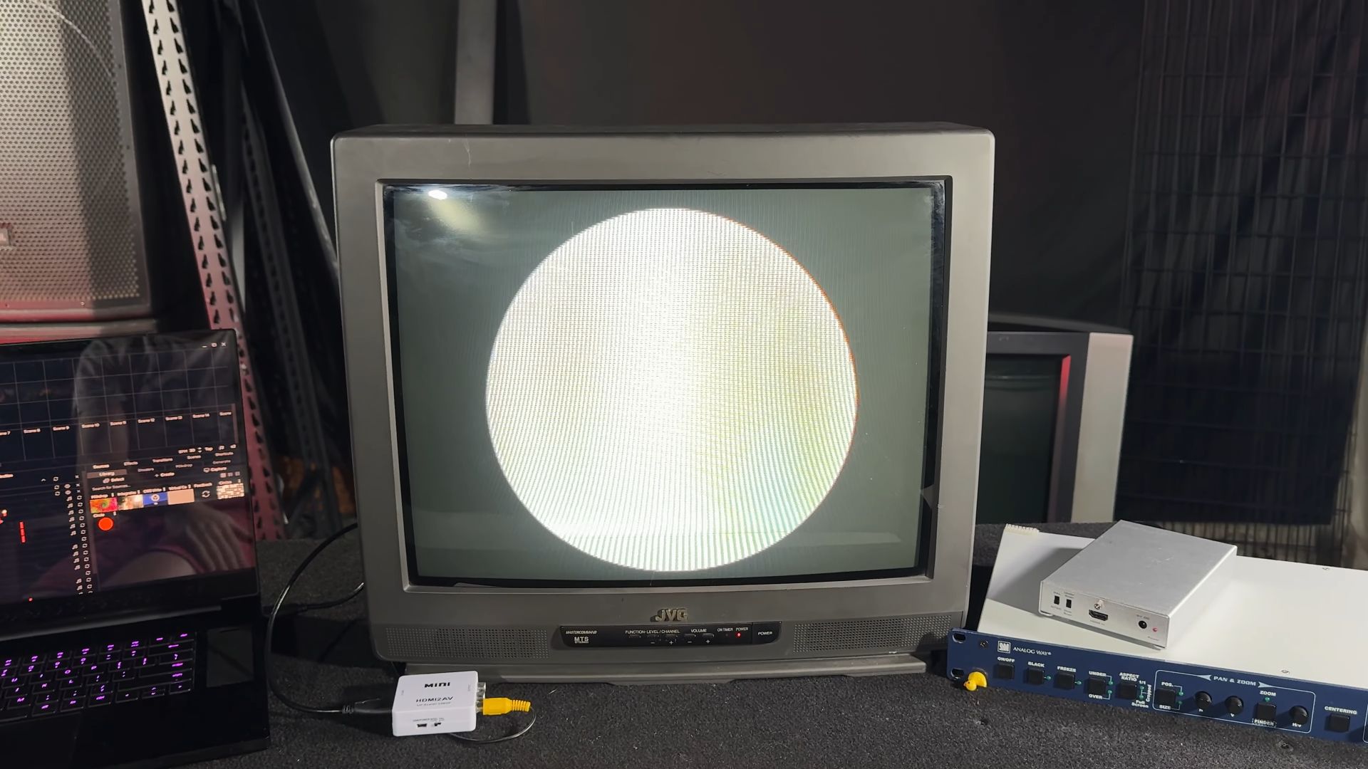 A vintage JVC CRT television displaying a perfect circle, connected to a laptop via an HDMI to AV converter on a table.